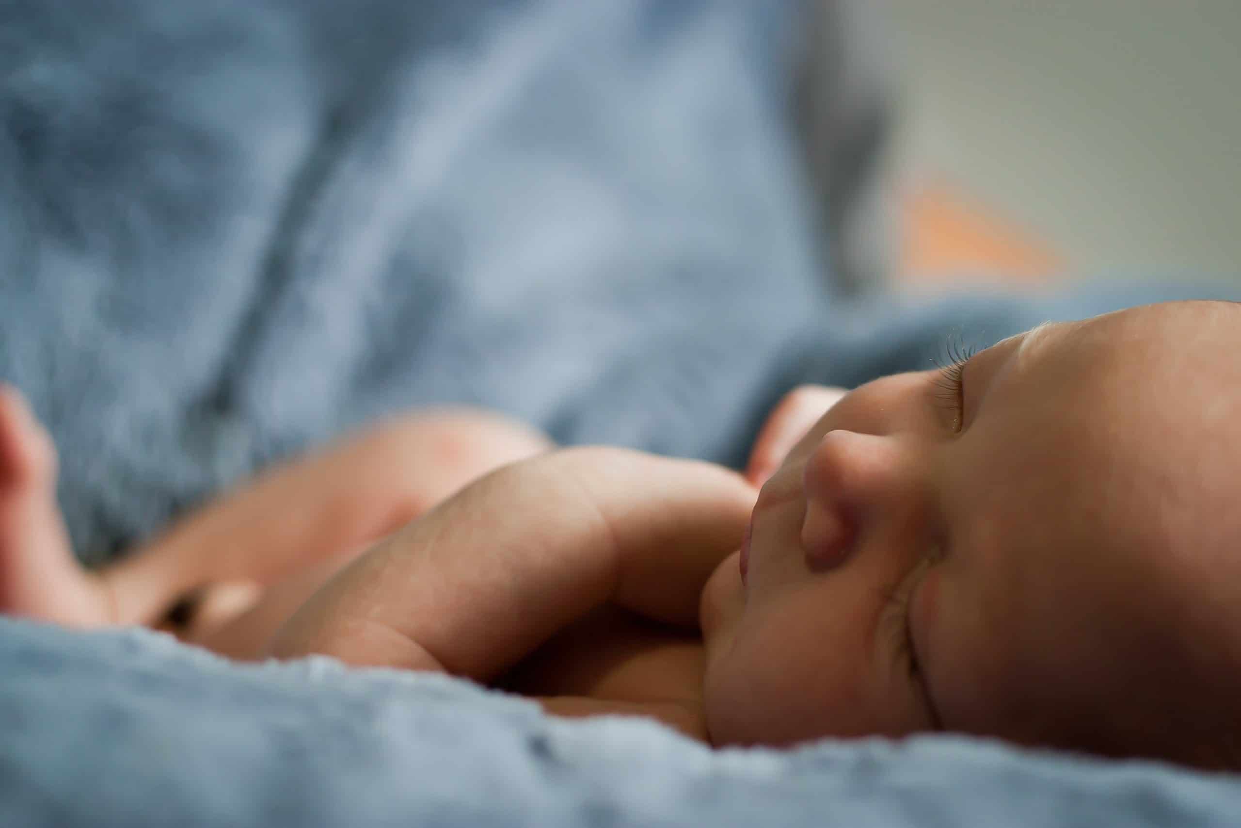 Sleepy newborn on blue sheet